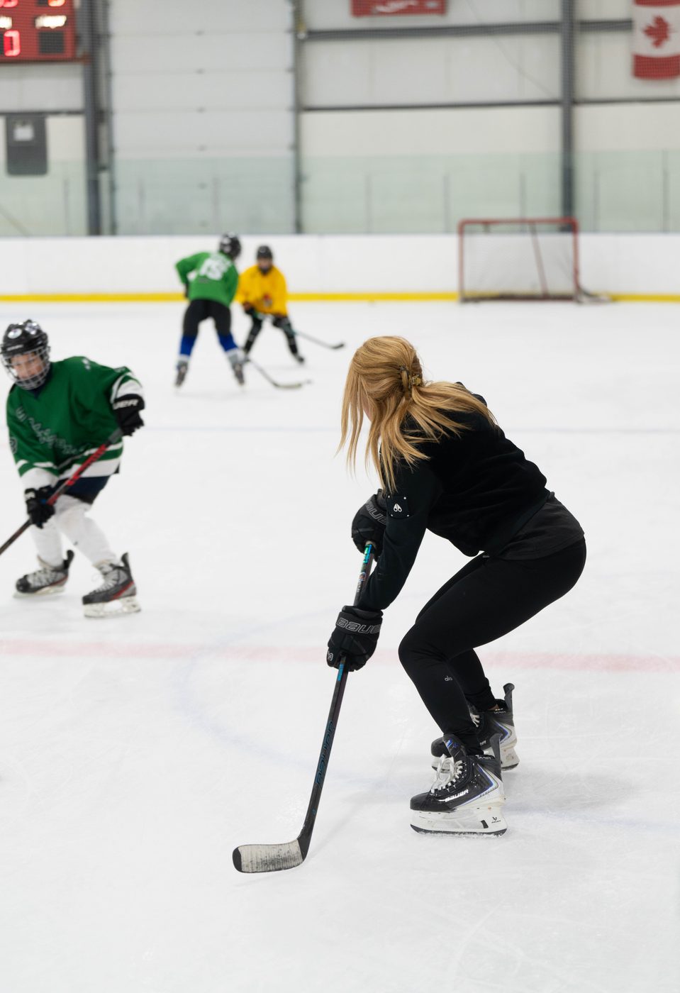 Coach Stacy Allen low in a crossover during a drill, with players lined up behind her