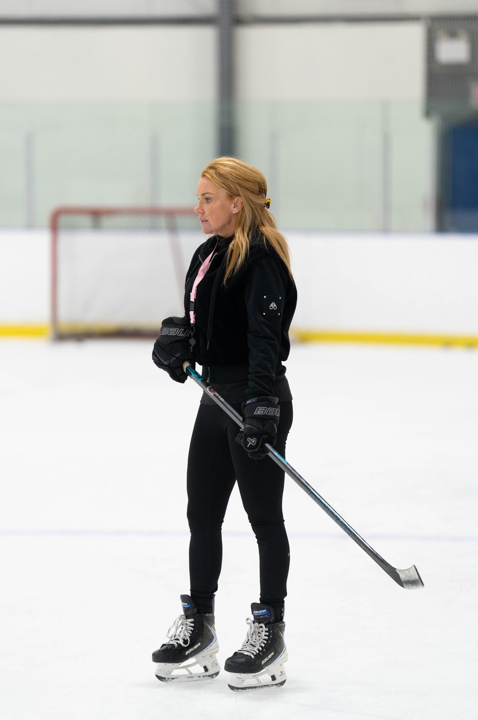 Stacy Allen standing at the net between drills, stick across her body